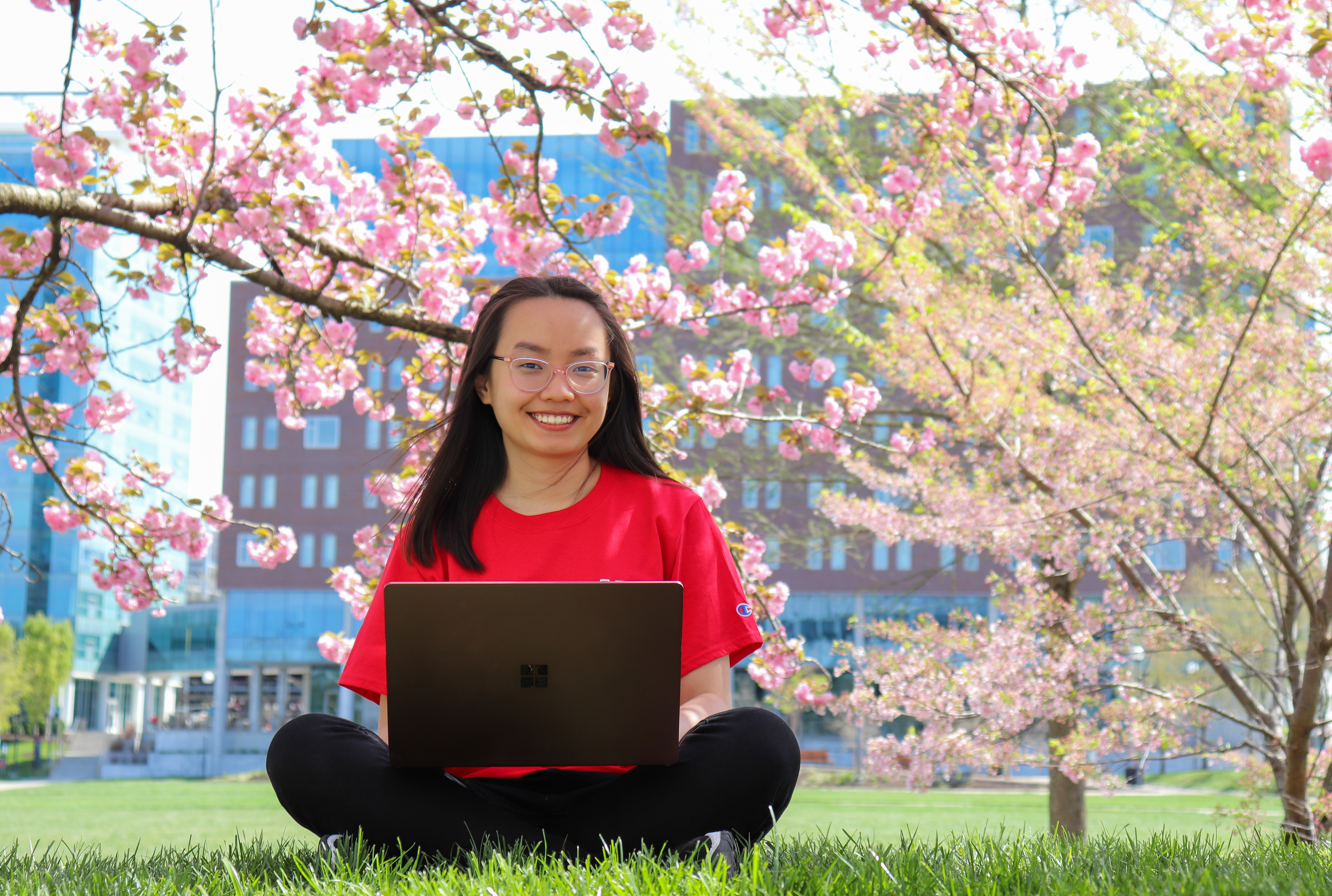 Two graduates pose in from of the Engineering building
